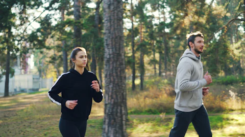 Férfi és nő együtt fut a parkban